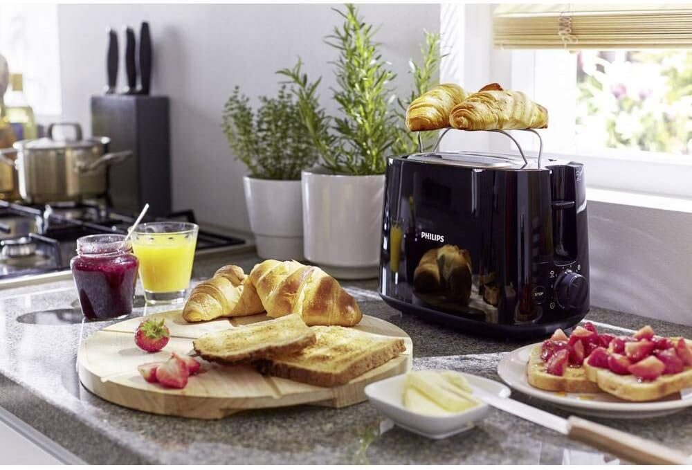 Grille-pain Philips Daily HD2581/90 noir sur un plan de travail avec croissants et toasts