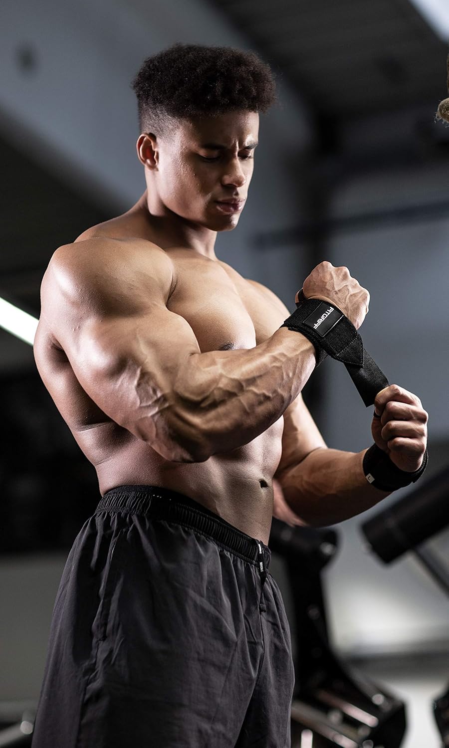 Homme en salle de musculation portant une bande de poignet Fitgriff noire